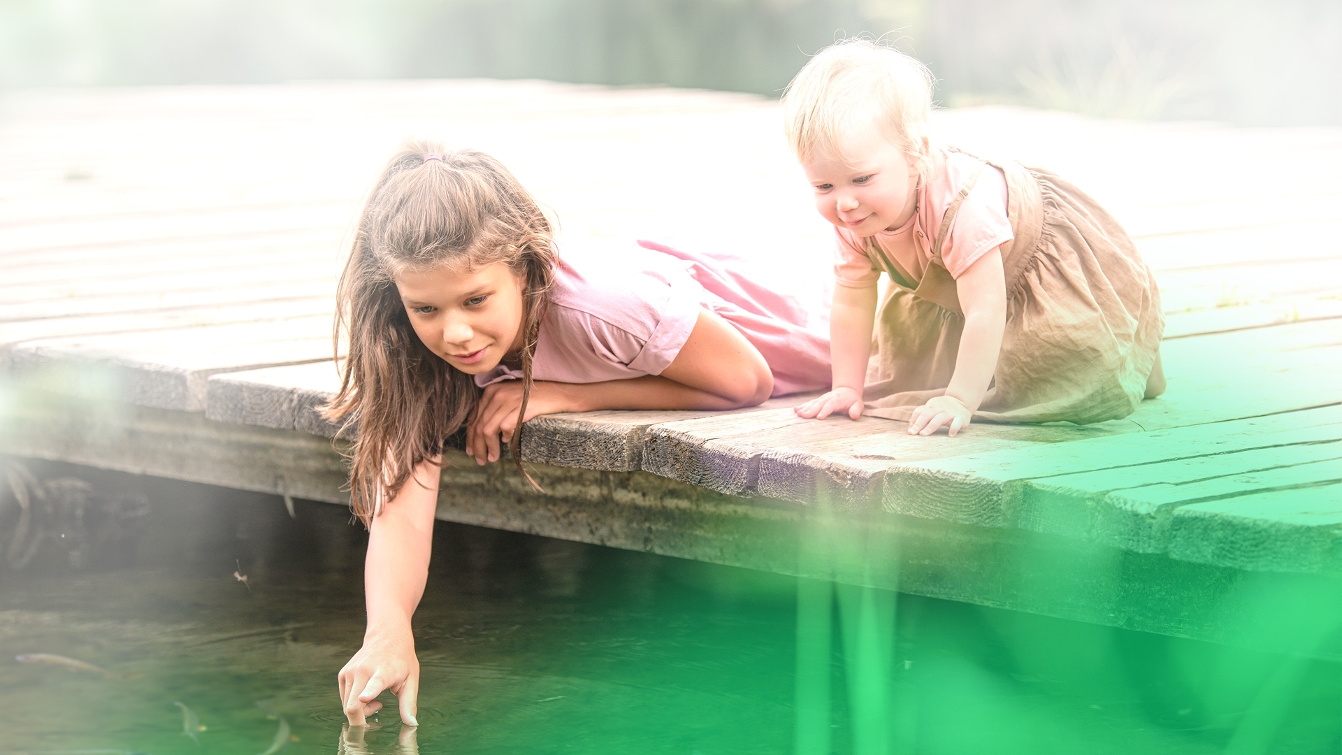 Zwei kleine Kinder spielen auf einem Steg am Wasser