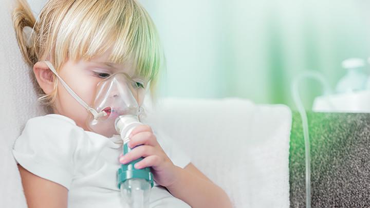 Junges Mädchen hält Inhalations-Gerät auf den Mund-Nase-Bereich