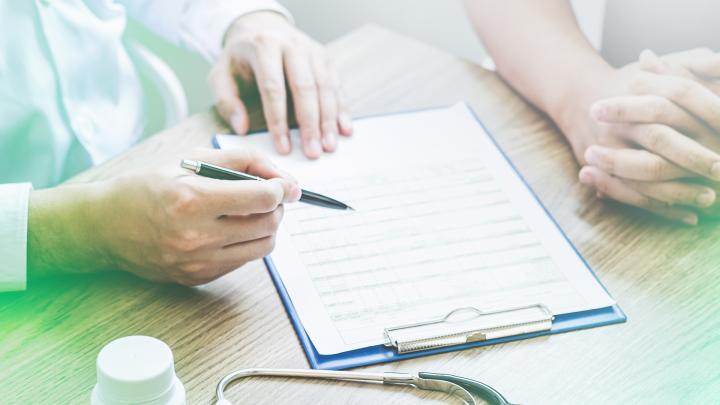 Hand mit Kugelschreiber zeigt auf ein blaues Klemmbrett