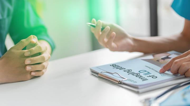 Fallbesprechung zur ILD-Therapie: Ärztliche Beratung mit Patientenunterlagen und Notizen am Tisch