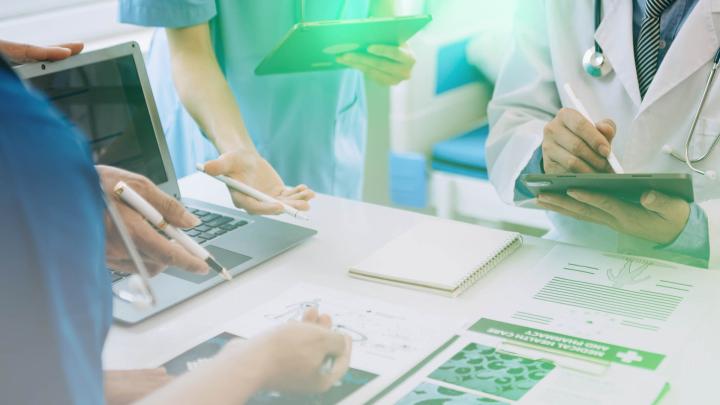 Ärzteteam bespricht medizinische Unterlagen und digitale Patienteninformationen im Krankenhaus.